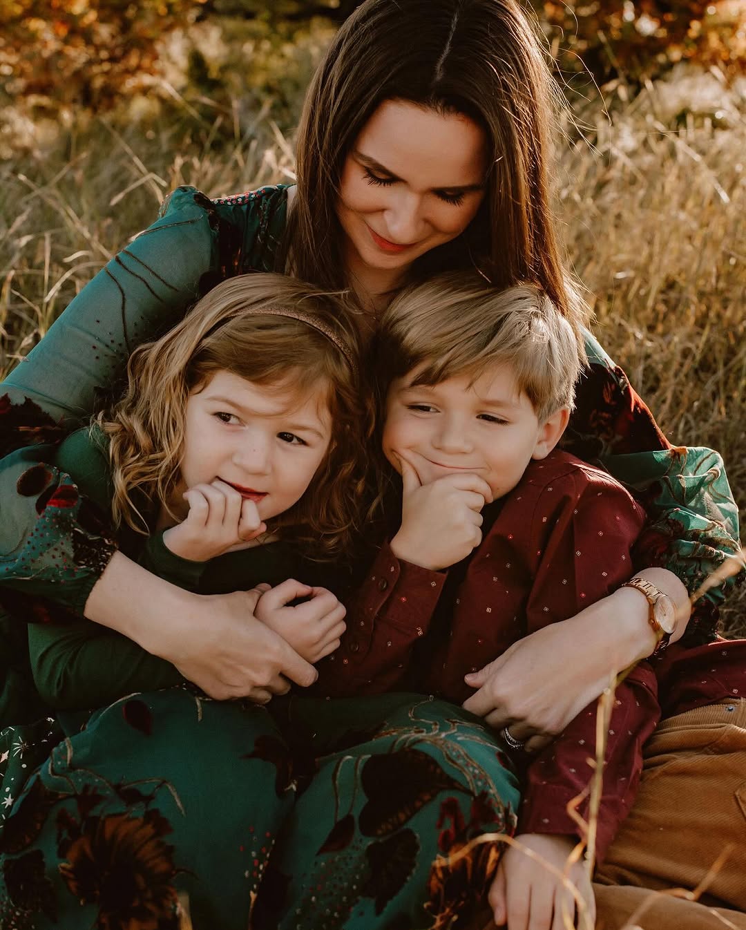Mom hugging her two children in a fall field