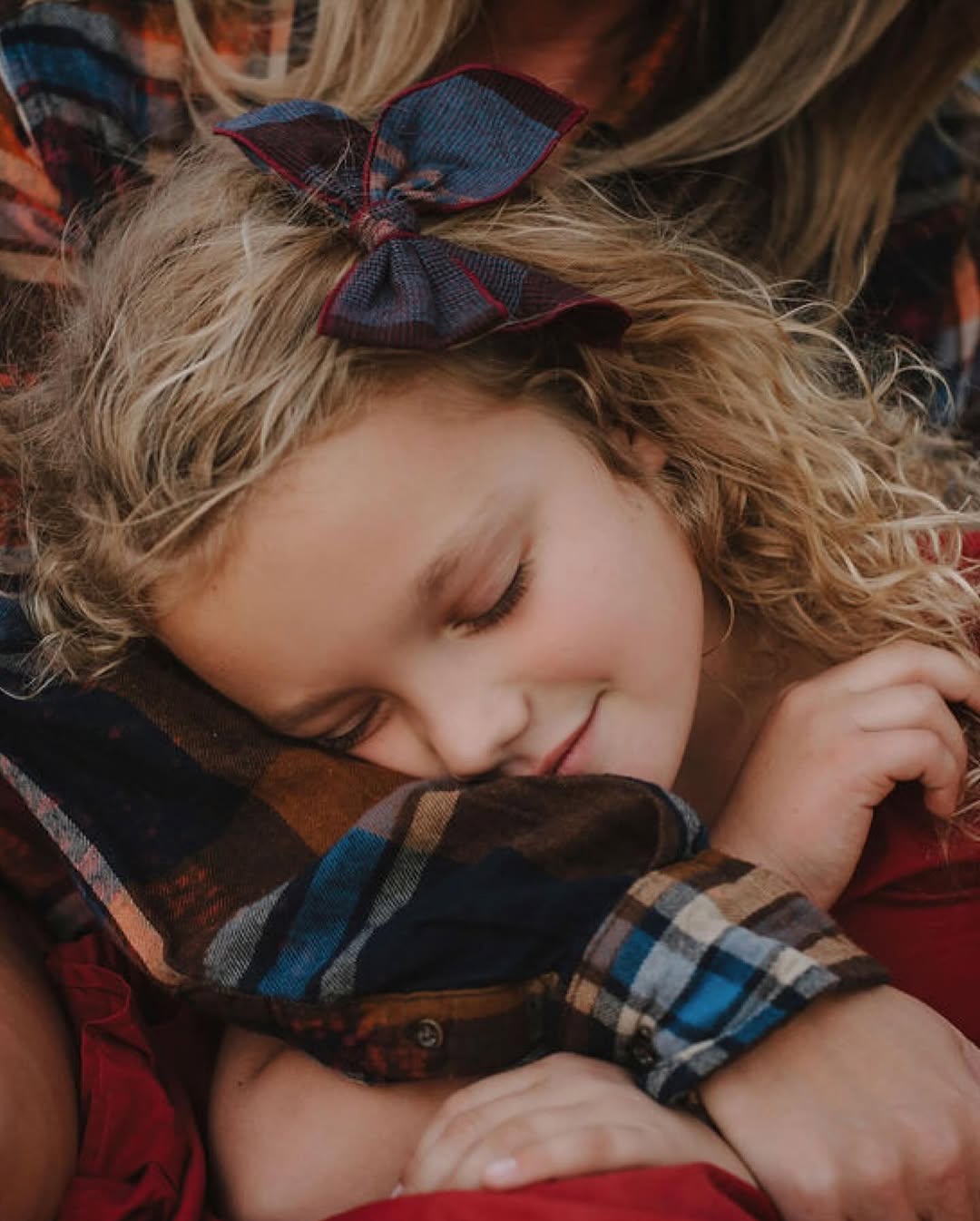 Sleeping child with a bow, held close